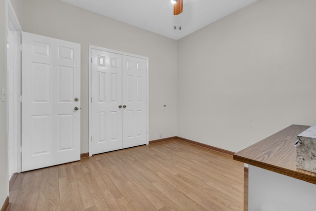 unfurnished bedroom with light wood-type flooring, ceiling fan, and a closet