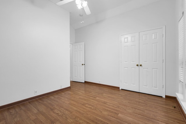 unfurnished bedroom featuring ceiling fan, wood-type flooring, a closet, and high vaulted ceiling