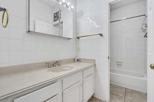 bathroom with tile patterned flooring, tile walls, tiled shower / bath combo, and vanity