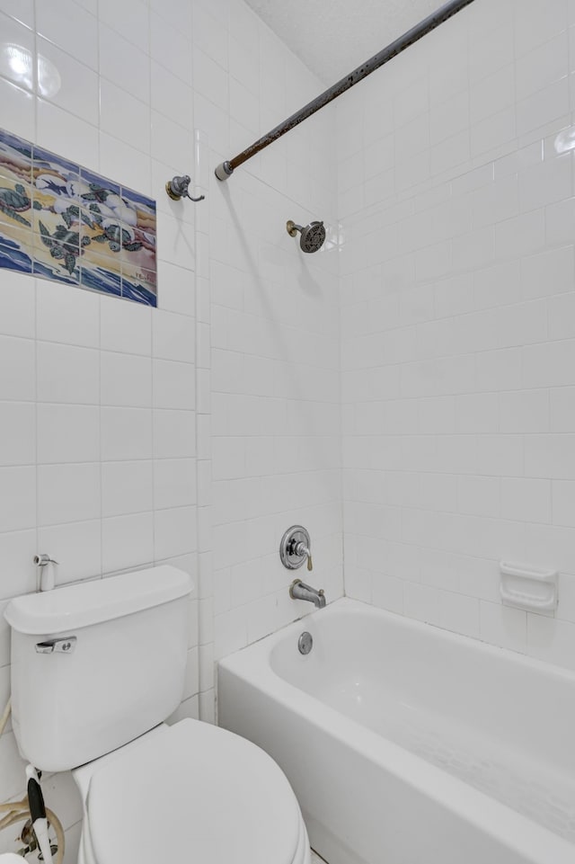 bathroom with tiled shower / bath combo, toilet, and tile walls