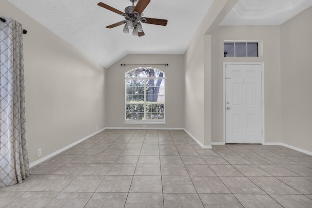 tiled empty room with lofted ceiling, a textured ceiling, and ceiling fan