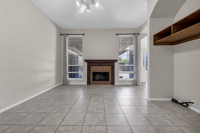 unfurnished living room with a textured ceiling, light tile patterned flooring, a tiled fireplace, and ceiling fan