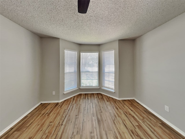 spare room with a textured ceiling and light wood-type flooring