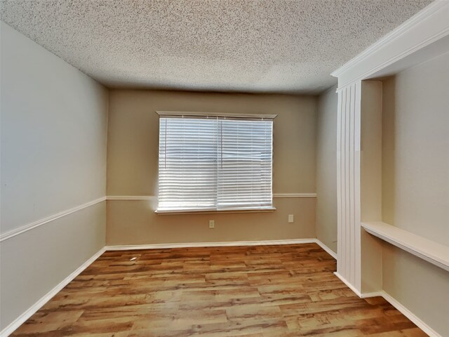 spare room featuring light hardwood / wood-style flooring and a textured ceiling