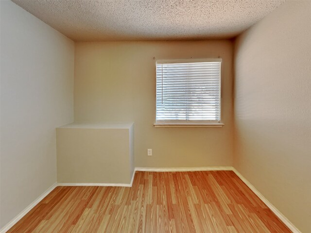 unfurnished room with a textured ceiling and wood-type flooring