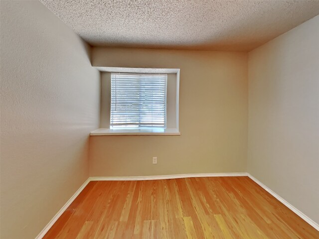 empty room with wood-type flooring and a textured ceiling