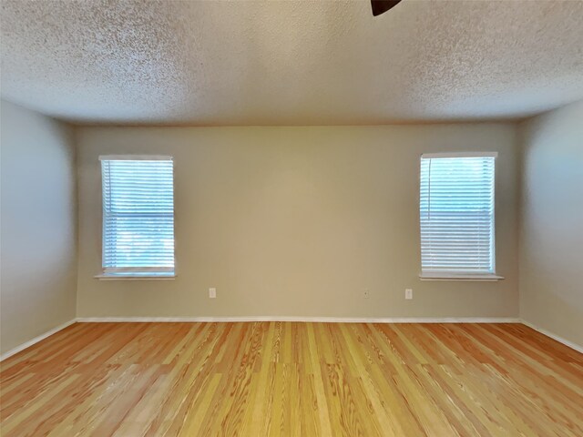 empty room featuring light wood-type flooring and a textured ceiling