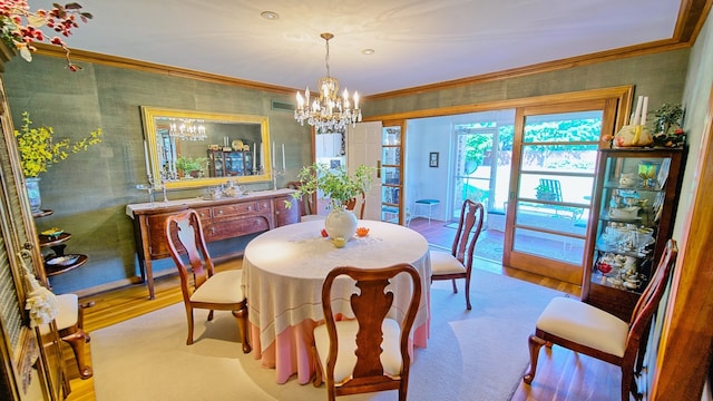 dining space with an inviting chandelier, crown molding, and light hardwood / wood-style flooring