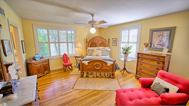 bedroom with light hardwood / wood-style floors, multiple windows, ceiling fan, and crown molding