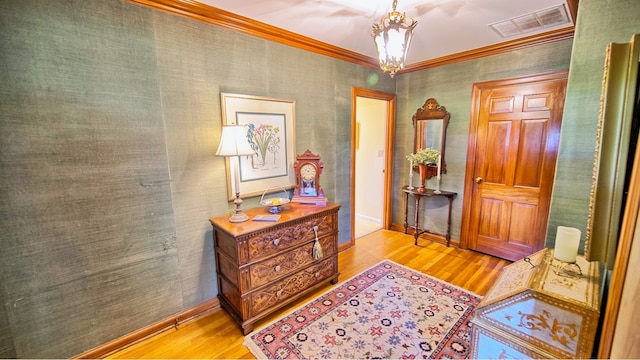 interior space with a chandelier, light wood-type flooring, and ornamental molding