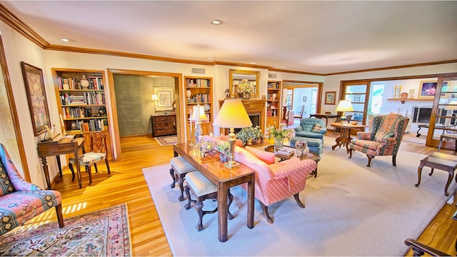 living room with built in shelves, light hardwood / wood-style flooring, and ornamental molding