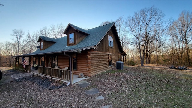 view of property exterior featuring a porch, roof with shingles, central AC unit, and log siding