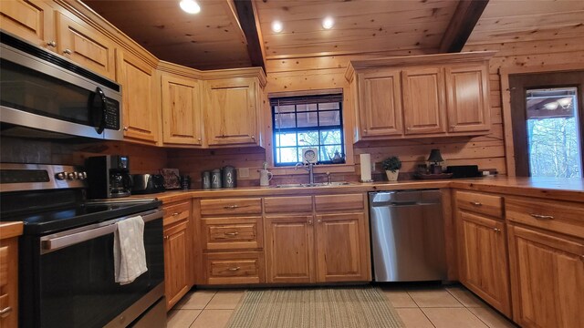 kitchen featuring light tile patterned floors, wood ceiling, stainless steel appliances, and a sink