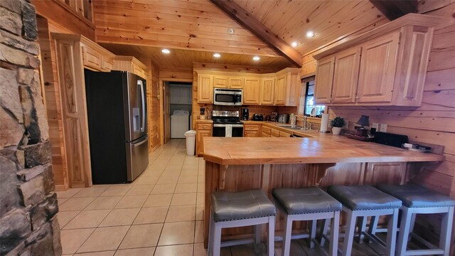 kitchen featuring tile countertops, stainless steel appliances, washer / dryer, wooden ceiling, and a peninsula