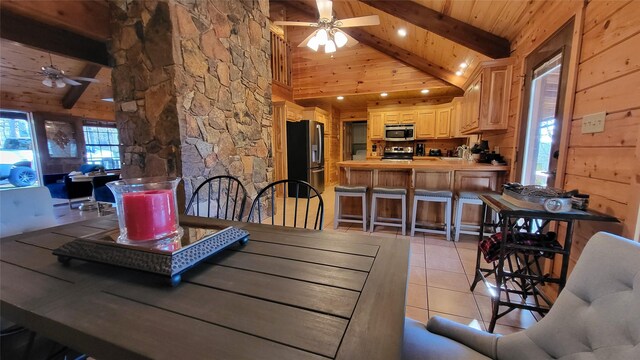 interior space with light tile patterned floors, wooden walls, a ceiling fan, wooden ceiling, and beam ceiling