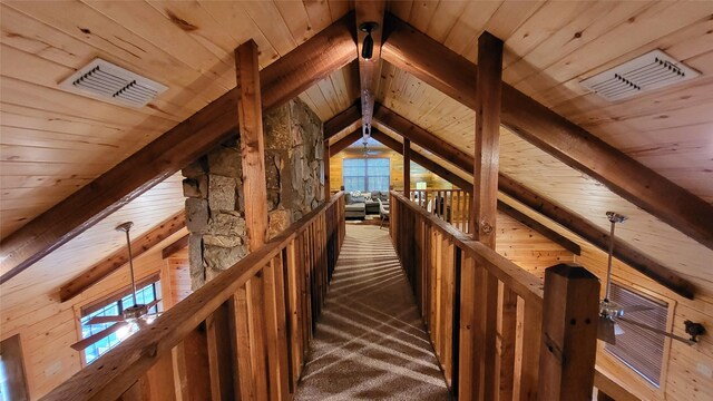 interior space featuring lofted ceiling with beams, visible vents, dark carpet, and an upstairs landing