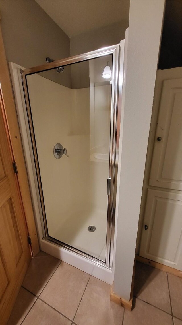 full bathroom with a stall shower and tile patterned flooring