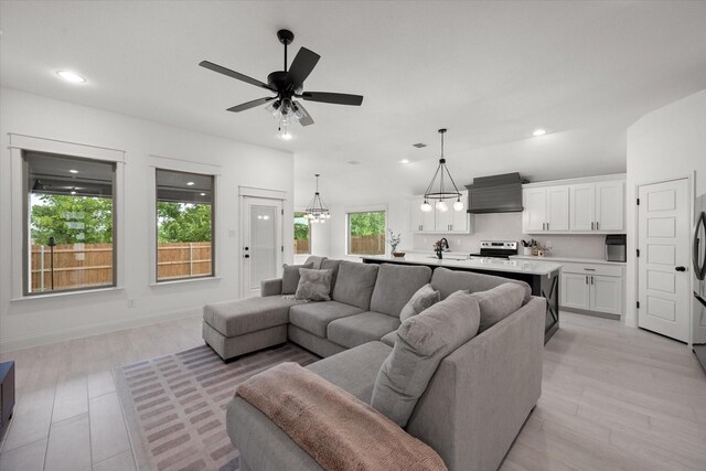 living room with light hardwood / wood-style flooring and ceiling fan with notable chandelier