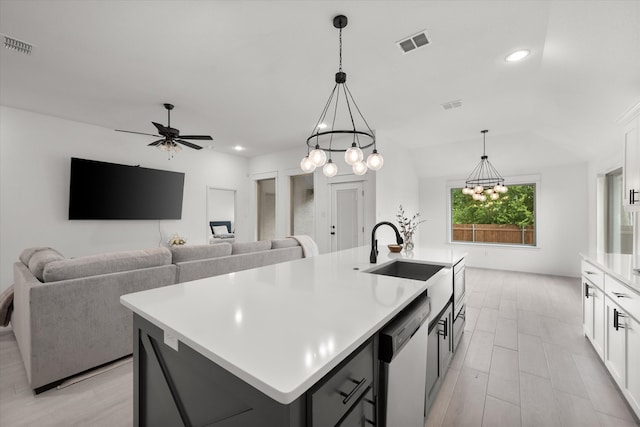 kitchen with dishwasher, decorative light fixtures, ceiling fan with notable chandelier, and a kitchen island with sink