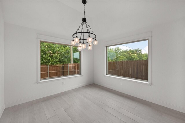 unfurnished room with light hardwood / wood-style flooring and an inviting chandelier