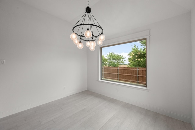 spare room featuring light hardwood / wood-style floors and an inviting chandelier