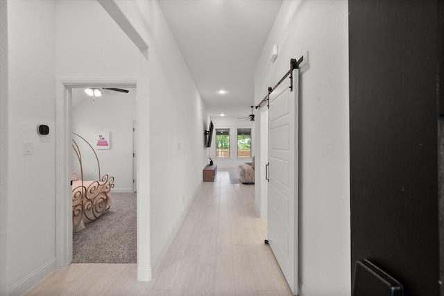 hall featuring light carpet and a barn door