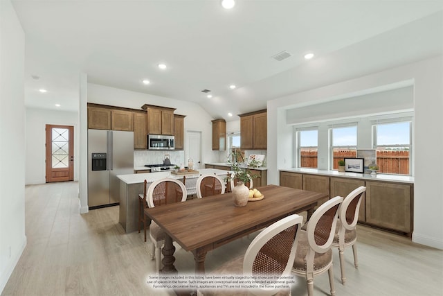 dining area with sink, light hardwood / wood-style flooring, and vaulted ceiling