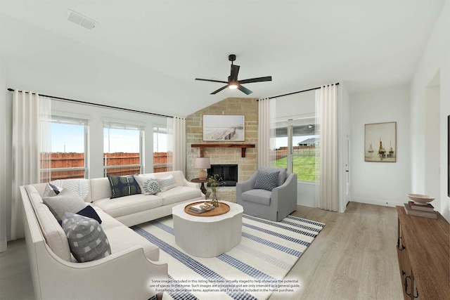 living room with a stone fireplace, lofted ceiling, ceiling fan, and light hardwood / wood-style flooring