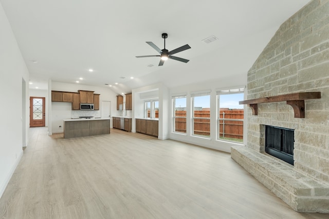 unfurnished living room with ceiling fan, a fireplace, and light hardwood / wood-style floors