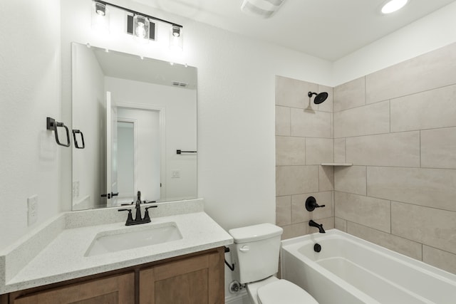 full bathroom featuring tiled shower / bath, vanity, and toilet