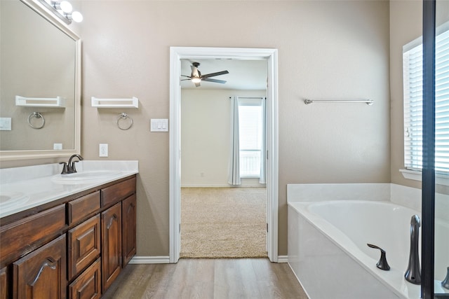 bathroom featuring hardwood / wood-style flooring, a healthy amount of sunlight, a tub, and ceiling fan