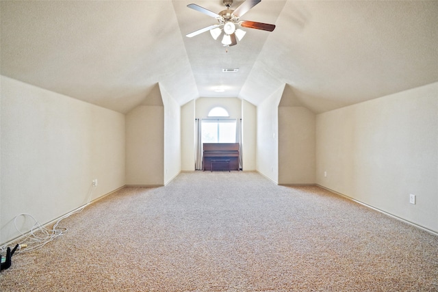 additional living space featuring light carpet, ceiling fan, lofted ceiling, and a textured ceiling