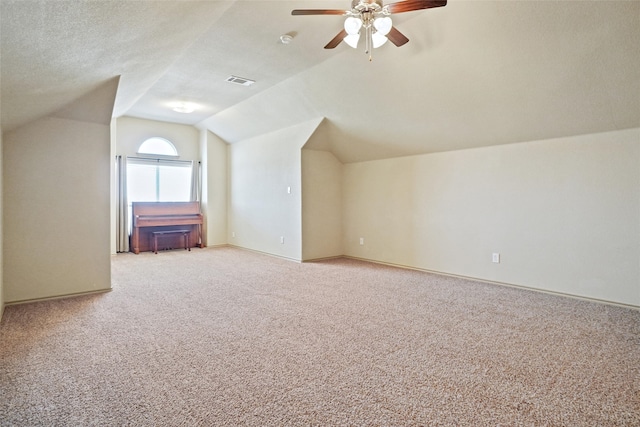 bonus room featuring ceiling fan, light carpet, vaulted ceiling, and a textured ceiling