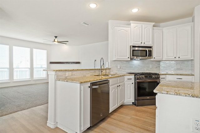 kitchen with appliances with stainless steel finishes, light hardwood / wood-style flooring, sink, decorative backsplash, and ceiling fan