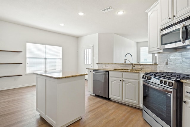 kitchen featuring light hardwood / wood-style floors, appliances with stainless steel finishes, a wealth of natural light, and decorative backsplash