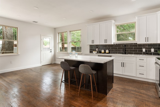 kitchen with sink, white cabinetry, a center island, and backsplash