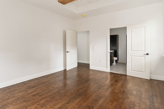 unfurnished bedroom featuring connected bathroom and dark hardwood / wood-style flooring