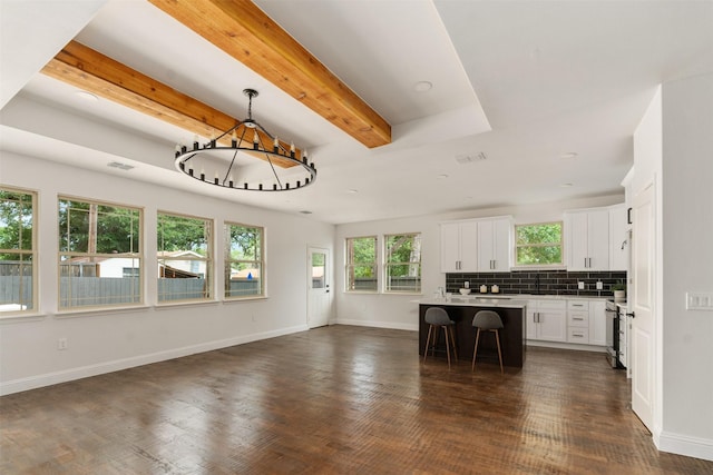 kitchen with a kitchen bar, hanging light fixtures, beam ceiling, white cabinets, and a center island