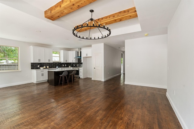 kitchen with wall chimney exhaust hood, pendant lighting, backsplash, a kitchen island, and white cabinetry