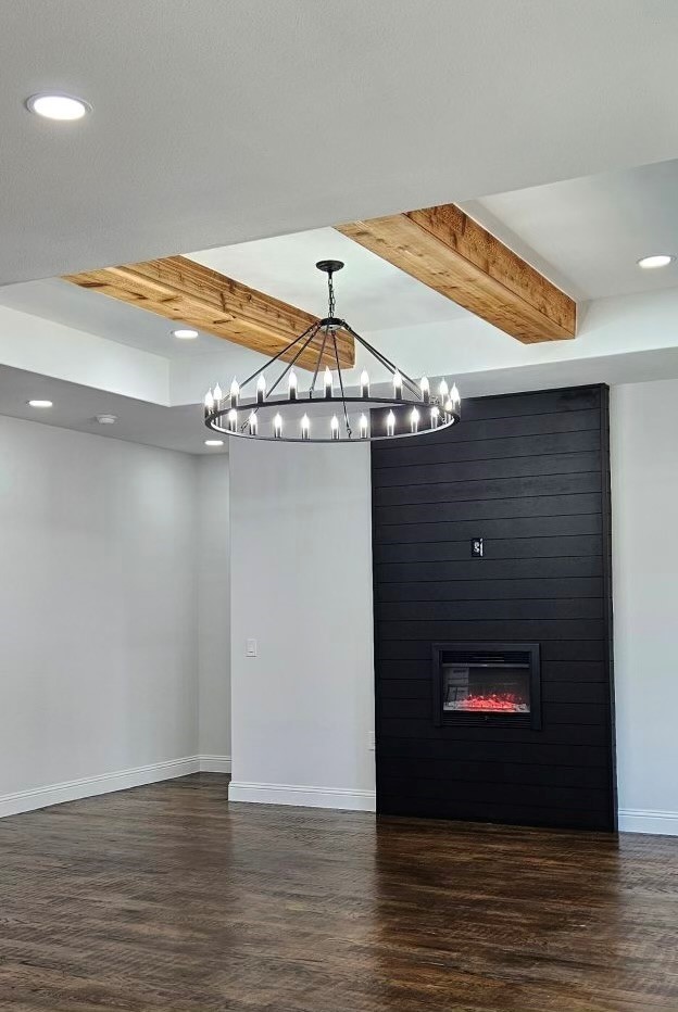 empty room featuring beam ceiling, dark wood-type flooring, and a large fireplace