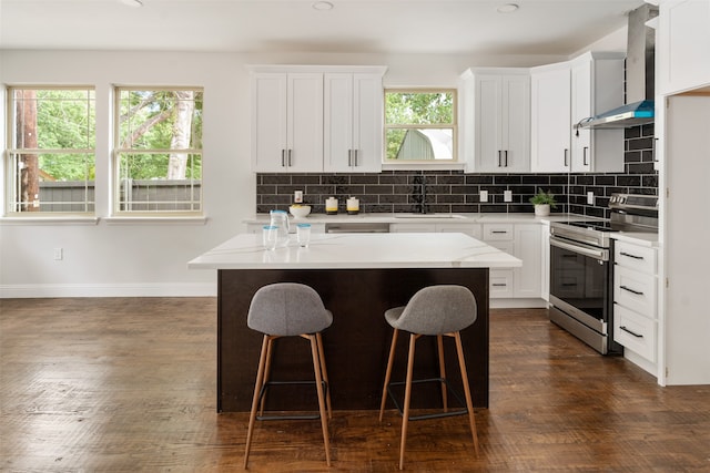 kitchen with stainless steel electric range, white cabinets, and wall chimney range hood