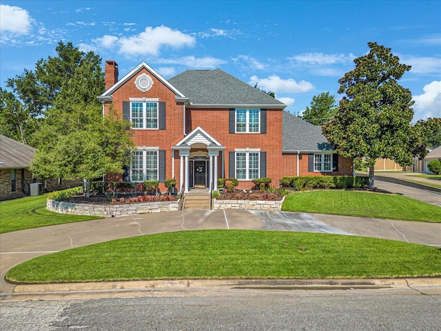 colonial-style house with a front lawn and central air condition unit