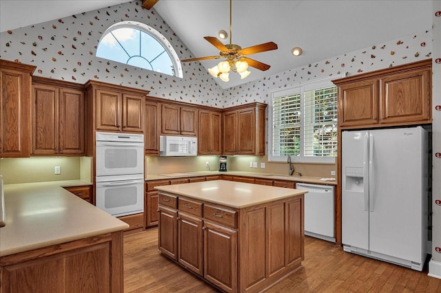 kitchen featuring beam ceiling, sink, white appliances, and light hardwood / wood-style floors