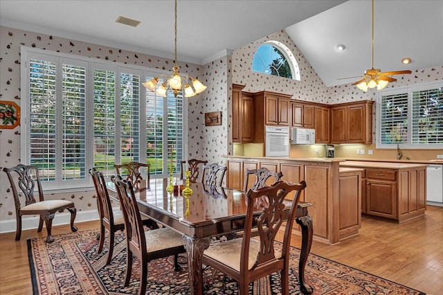 dining space featuring sink, high vaulted ceiling, ornamental molding, light hardwood / wood-style floors, and ceiling fan with notable chandelier