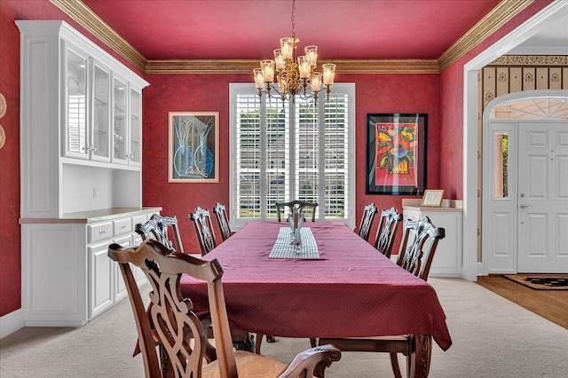 carpeted dining space with a notable chandelier and ornamental molding