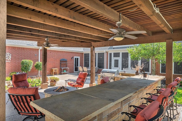 view of patio / terrace featuring ceiling fan, area for grilling, an outdoor bar, and a fire pit