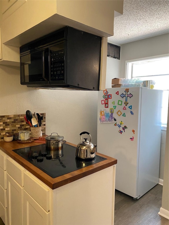 kitchen featuring white cabinetry, a textured ceiling, dark hardwood / wood-style floors, decorative backsplash, and black appliances