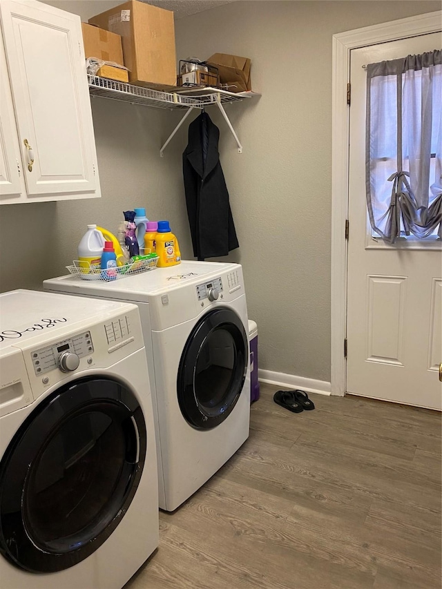 laundry room with cabinets, independent washer and dryer, and light wood-type flooring