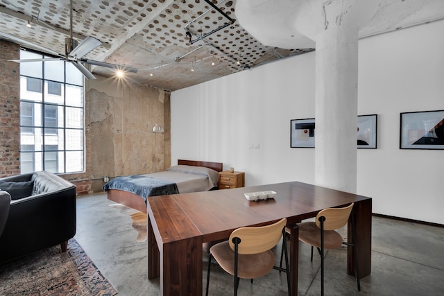 dining area featuring ceiling fan, concrete flooring, rail lighting, and a high ceiling