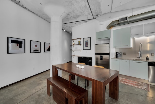 dining space with sink, concrete flooring, and decorative columns